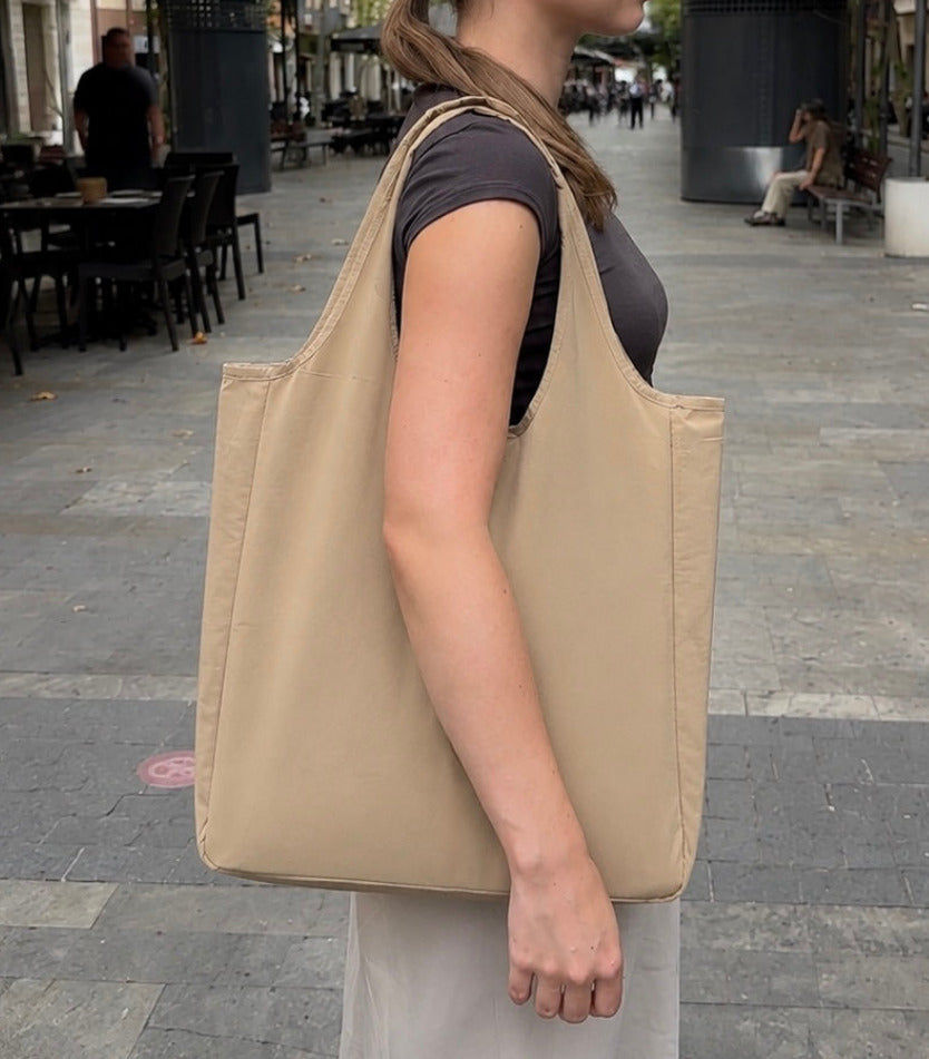 Beige foldable tote worn over the shoulder